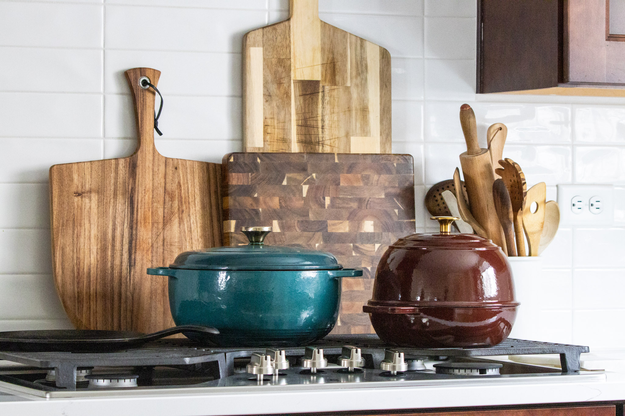 A still life of cookware and cutting boards on the gas stove